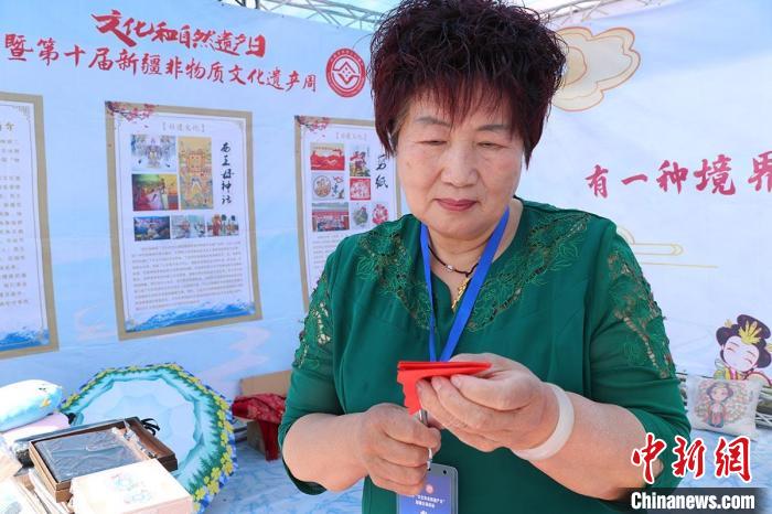 新疆阜康市剪紙非遺傳承人楊含萍向觀眾介紹剪紙藝術(shù)。　閆文陸 攝