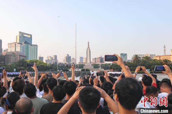 圖為不少市民在八一廣場(chǎng)上觀看升旗儀式?！⒘巍z