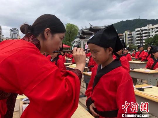 資料圖：在“點朱啟智”環(huán)節(jié)，先生在學童的額心點上朱砂，寓意孩子從此開啟智慧，目明心亮。曉東 攝