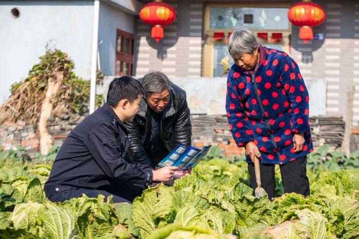 　江蘇省泰州市海陵區(qū)蘇陳派出所民警在蘇陳社區(qū)田間地頭向農(nóng)戶進(jìn)行普法宣傳(2021年12月4日攝)。新華社發(fā)(湯德宏 攝)