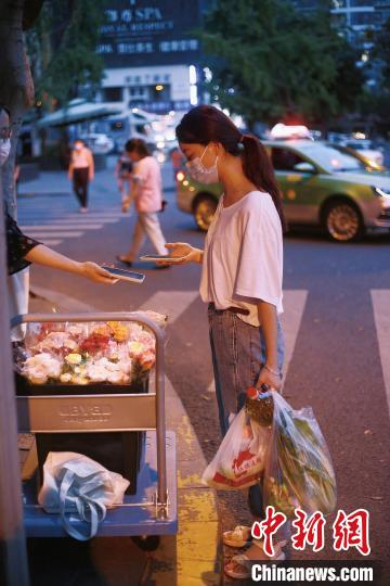 手提兩袋蔬菜的成都市民在選購(gòu)鮮花?！∈茉L者供圖