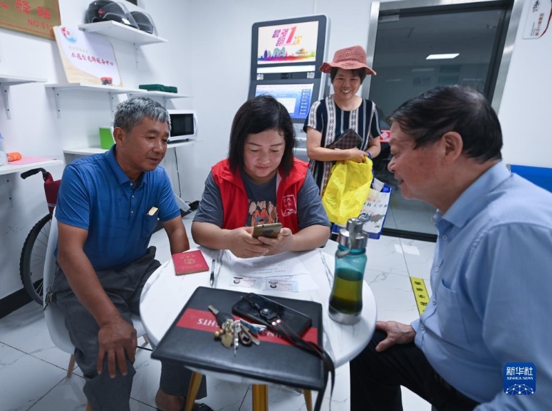 在浙江省杭州市臨安區(qū)玲瓏街道東山社區(qū)便民服務(wù)站，黨員志愿者幫助居民填寫公租房申請資料（2022年8月17日攝）。新華社記者 徐昱 攝