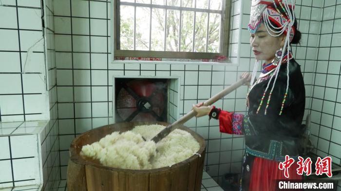 圖為藍(lán)春花鏟出煮熟的糯米進(jìn)行釀酒?！∮浾呷A山 攝