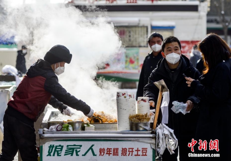 資料圖：外出購物的市民購買品嘗街頭小吃。 劉新 攝