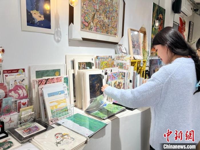 圖為藝術(shù)品商店內(nèi)，顧客挑選插畫作品?！＄婌?攝