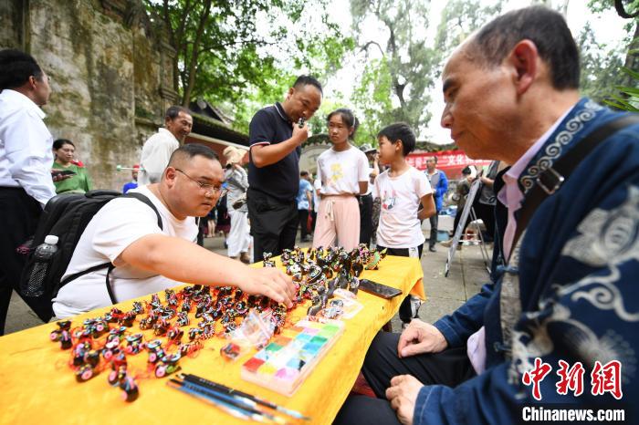 5月26日，游客在貴州黃平縣飛云崖景區(qū)購(gòu)買非遺產(chǎn)品泥哨?！￡愋⑿?攝