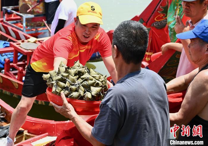 工作人員向龍舟上傳送粽子?！⊥鯑|明 攝