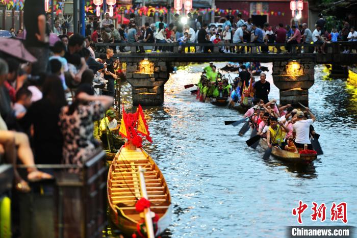 圖為6月17日晚，華燈初上，數(shù)十條龍舟在福建長樂江田鎮(zhèn)三溪村的溪中競(jìng)渡。　張斌 攝