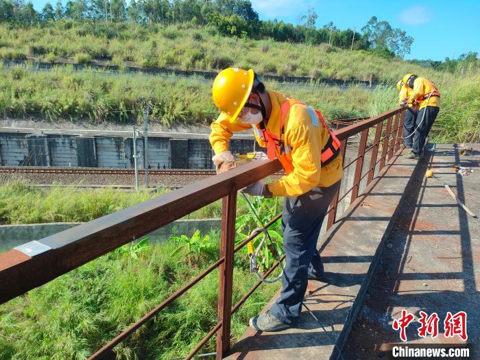 圖為高溫下南寧工務(wù)段橋梁工全副武裝對(duì)鐵路橋梁人行道欄桿打磨除銹?！●T博 攝