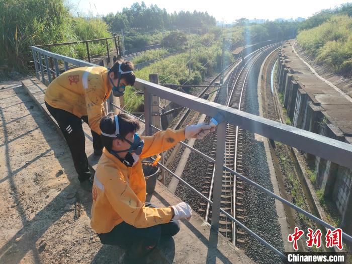 圖為高溫下南寧工務(wù)段橋梁工全副武裝對(duì)鐵路橋梁人行道欄桿打磨除銹?！●T博 攝