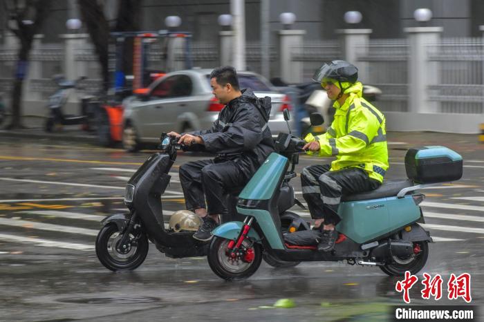 圖為海口市民冒雨出行。　駱云飛 攝