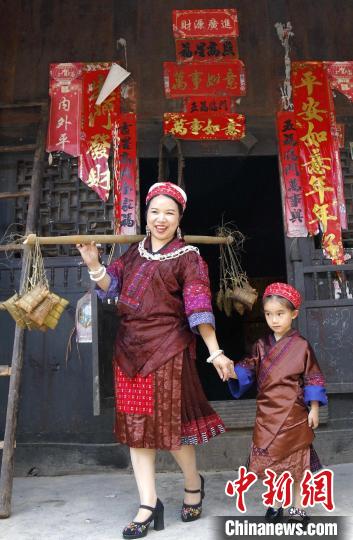 施秉縣楊柳塘鎮(zhèn)陸地坪苗寨苗族女同胞帶著包好的粽粑串門?！》盍?攝