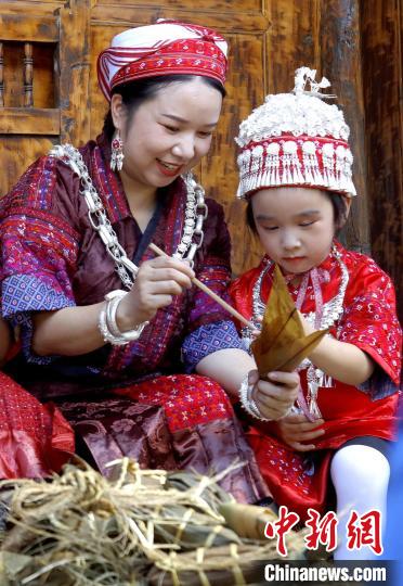 施秉縣楊柳塘鎮(zhèn)陸地坪苗寨一位苗族女子教孩子包粽粑。　奉力 攝