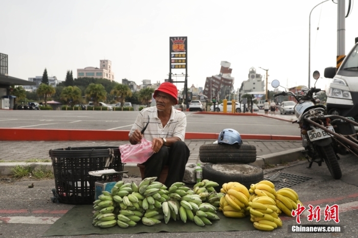 資料圖：臺灣花蓮市區(qū)博愛路早市，商販在街頭擺攤售賣水果，不遠處是因震傾斜嚴重的天王星大樓。 中新社記者 楊程晨 攝.jpg